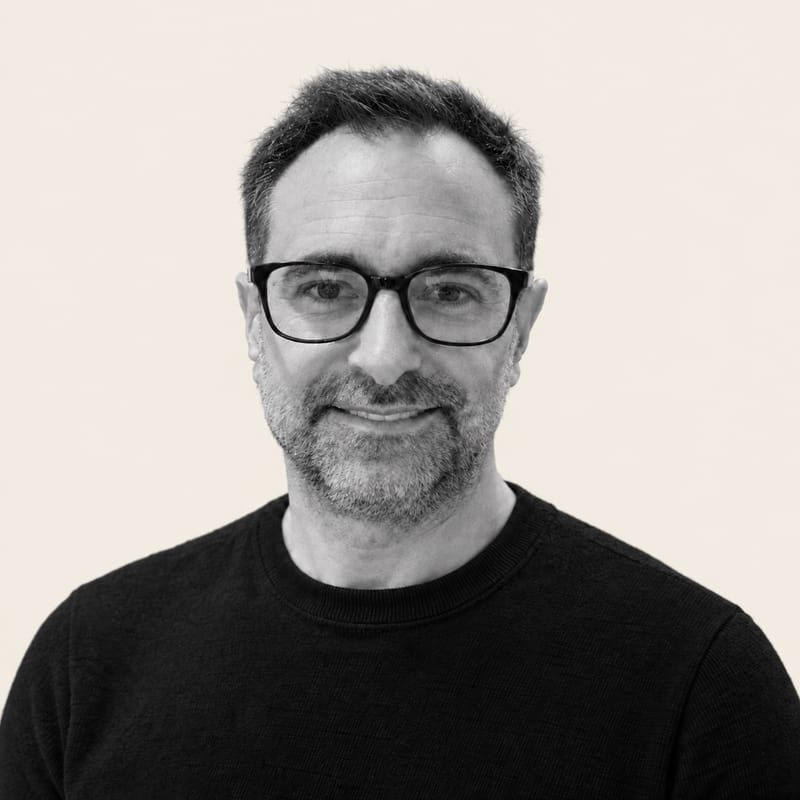 Portrait de Jean-Philippe Poisson, souriant, en noir et blanc sur fond crème.